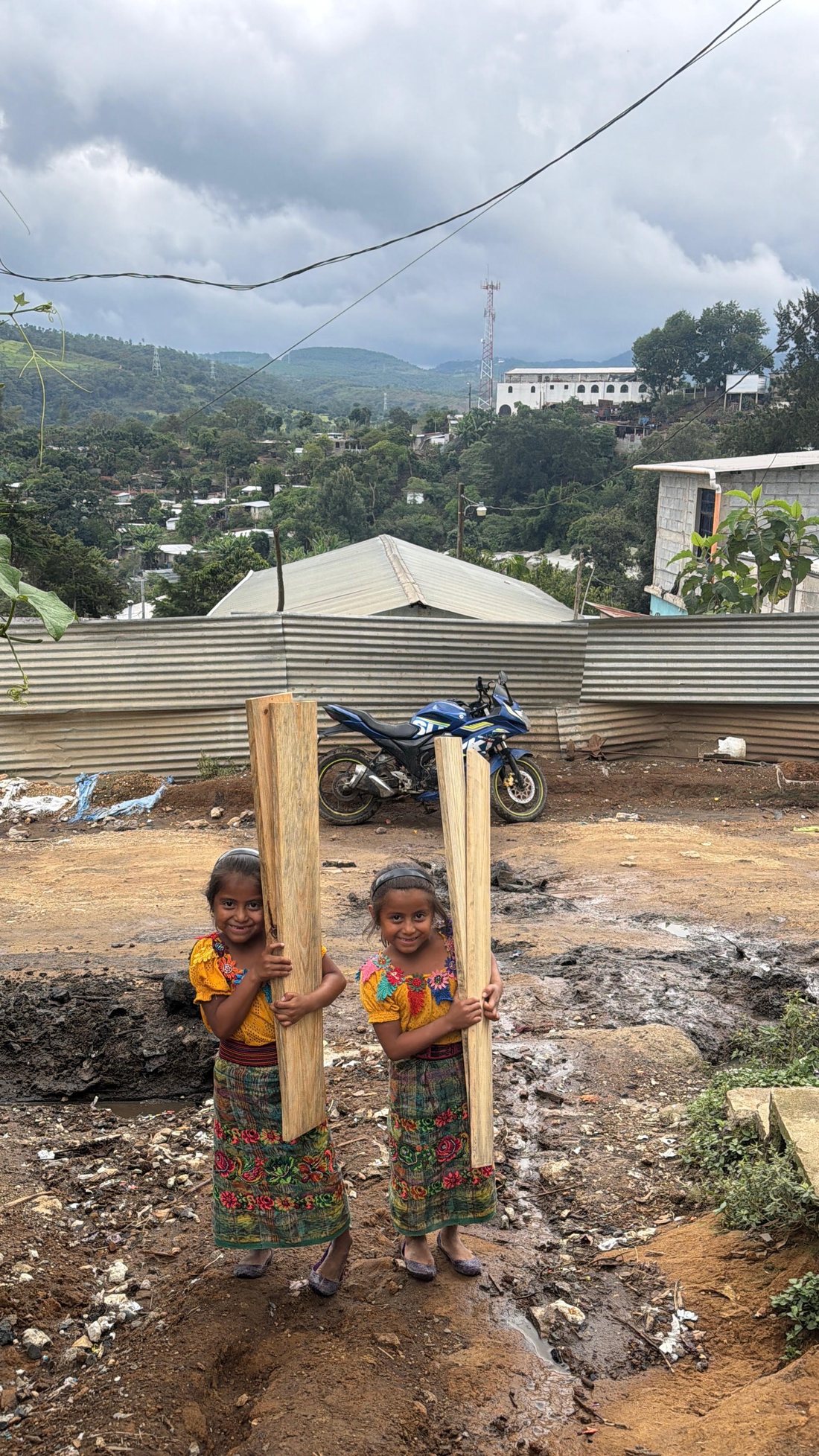 Two girls in Yalú carrying boards for their new beds